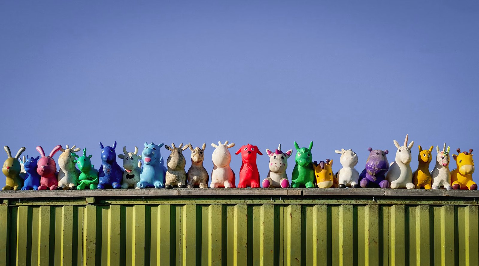 A long row of colourful toy animals, each one different, against blue sky